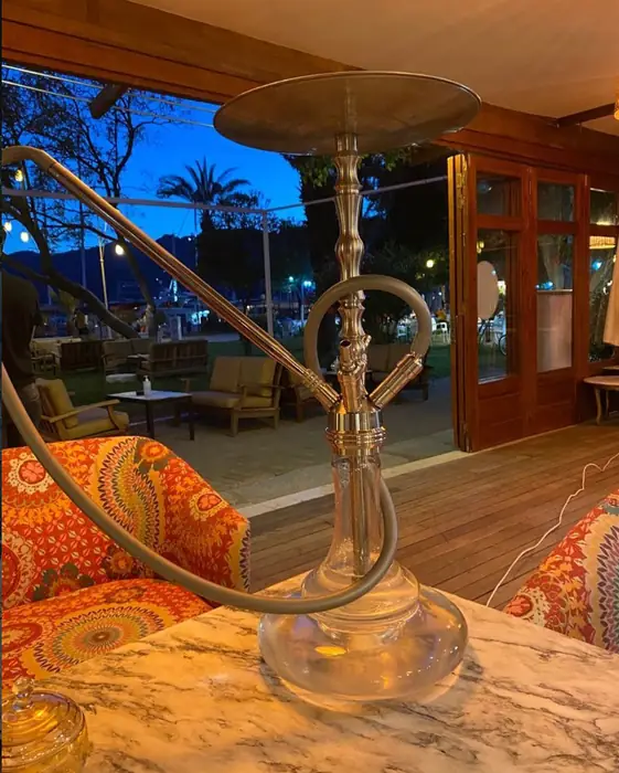 Mermer masada pirinç nargile ve akşamüstü marina manzarası